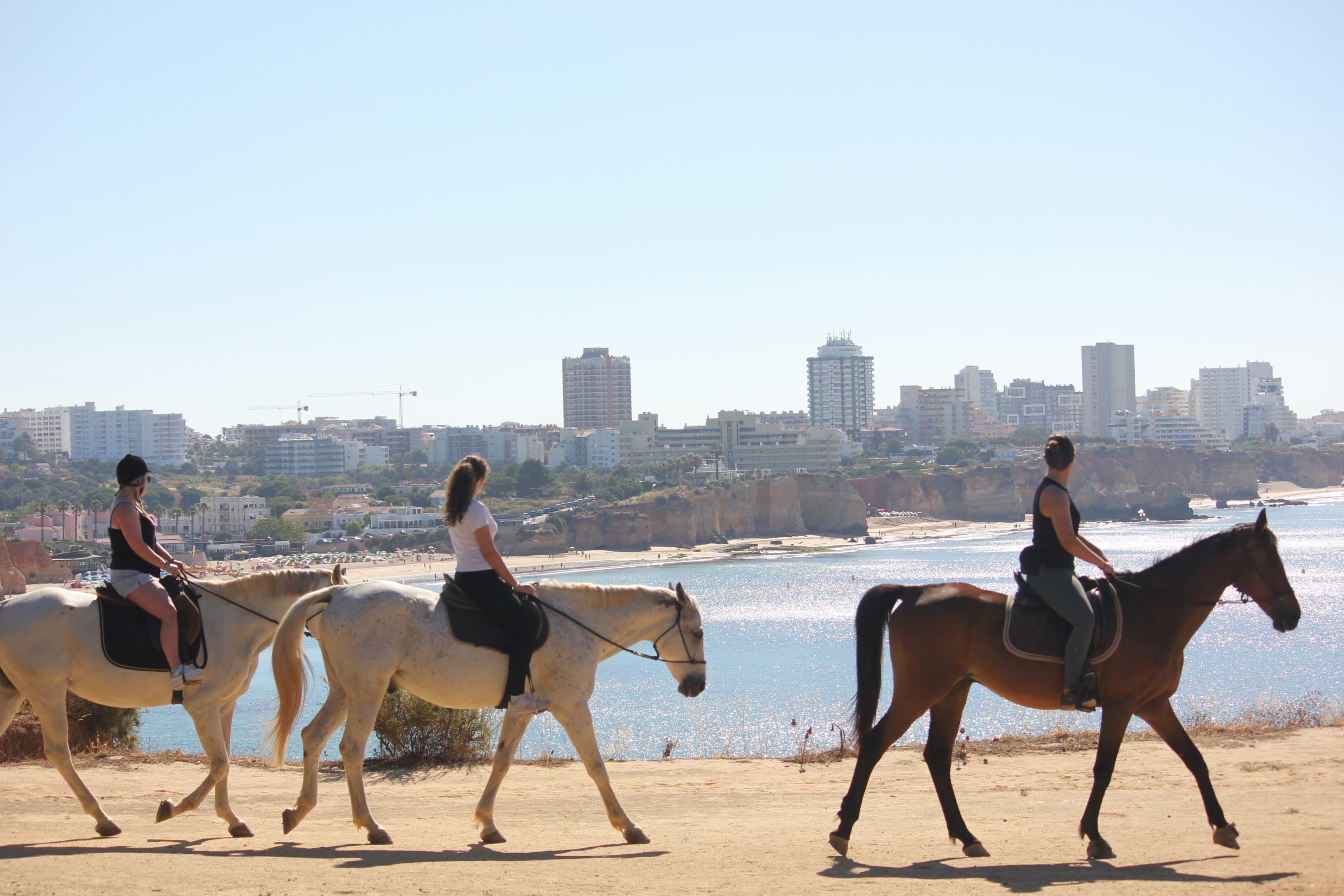 Horse riders on the Algarve coast with the Atlantic cliffs behind them